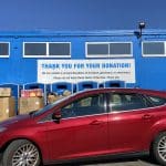 Car parked and being loaded with donations at a charity event.