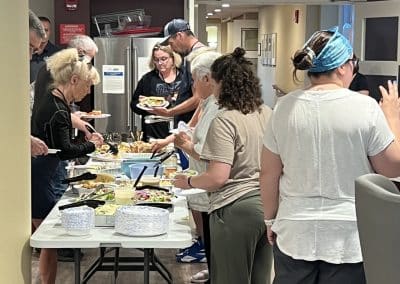 A group of guests at Hope Lodge Boston serve themselves from a buffet of dishes prepared by the PTP Gives Back and AWS MASS SMB teams, enjoying a meal together in a supportive environment.