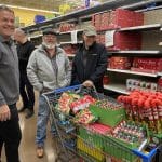 Rick, Mike, and Rich from the PeakPlus team pushing a shopping cart full of candy during a charity event at Matthew 25: Ministries.